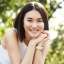 Beautiful asian woman sitting on bench and smiling. Modern girl resting in park on sunny summer day, looking happy.